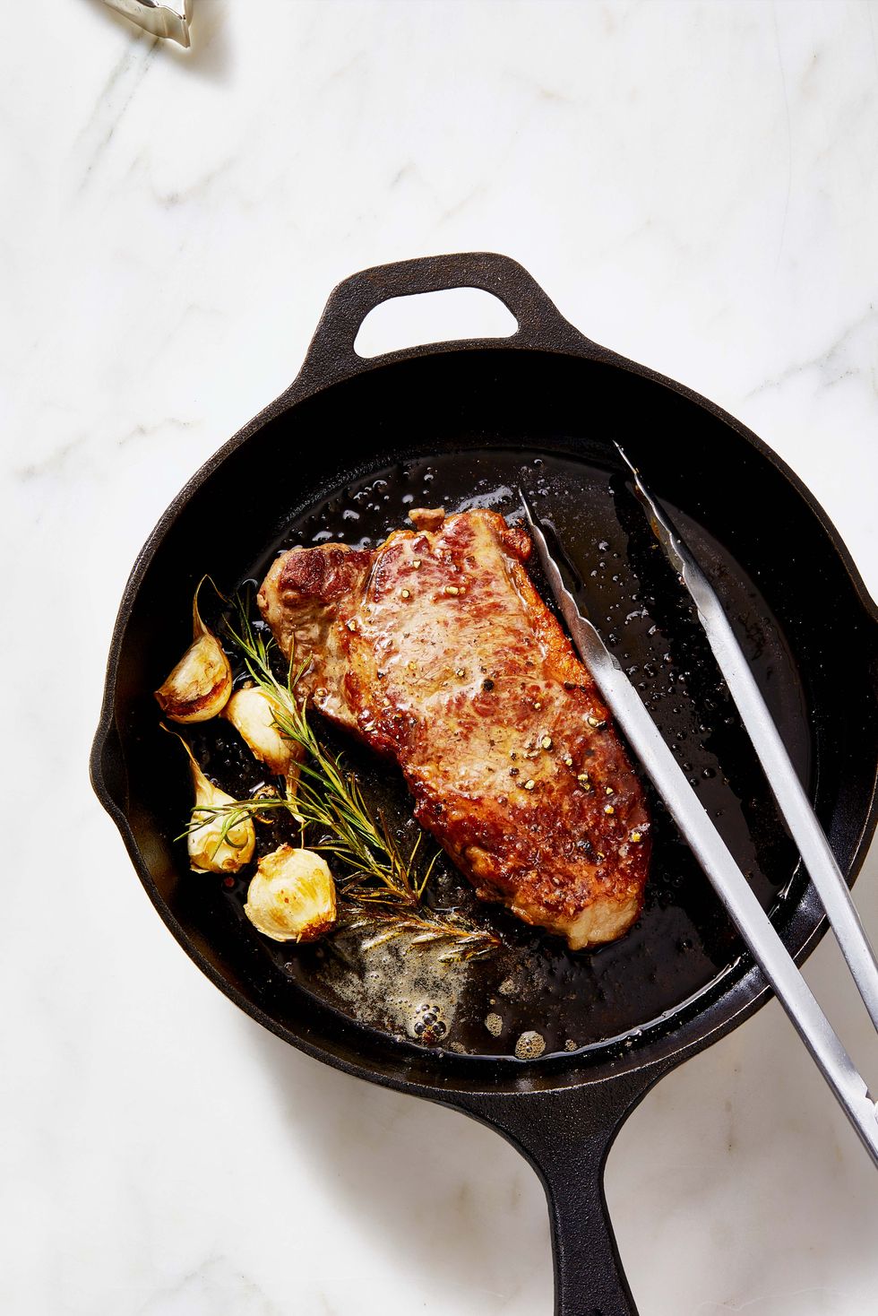 new york strip steak with rosemary and garlic on a cast iron skillet