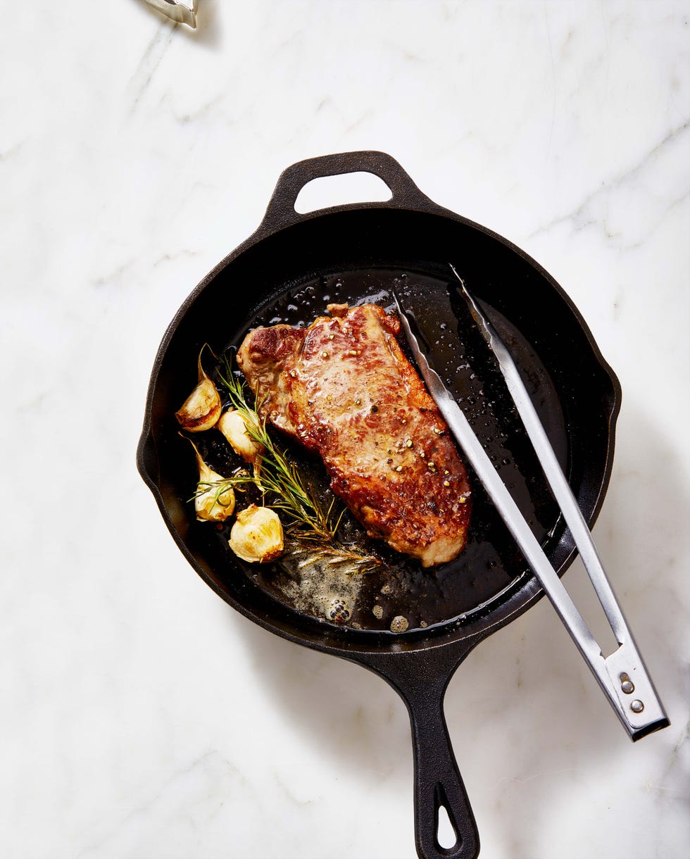 new york strip steak with rosemary and garlic on a cast iron skillet