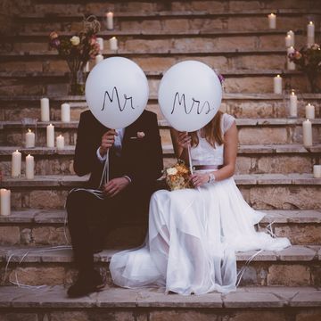 Newlywed couple sitting on steps and holding balloons