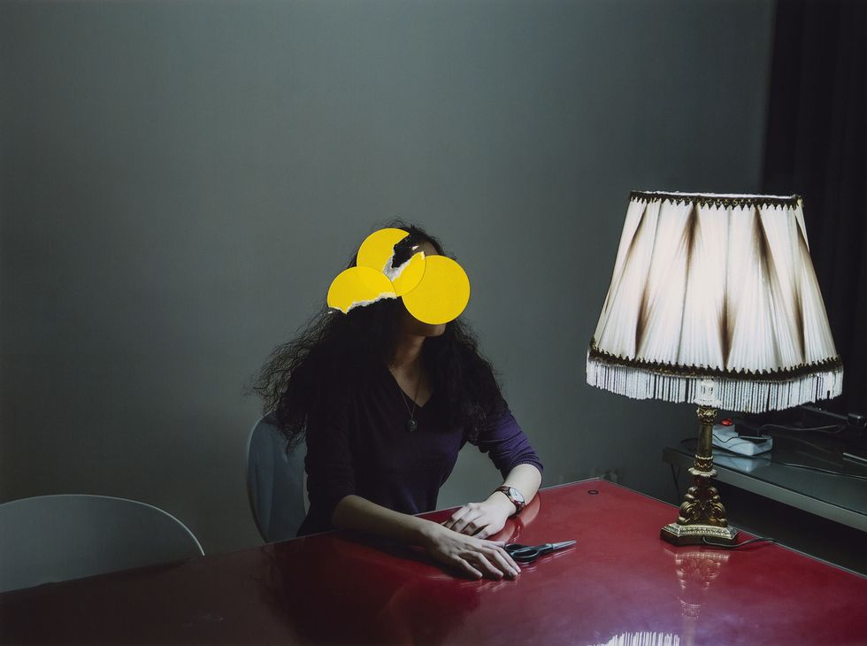 a person sitting at a table with a yellow mask on the face