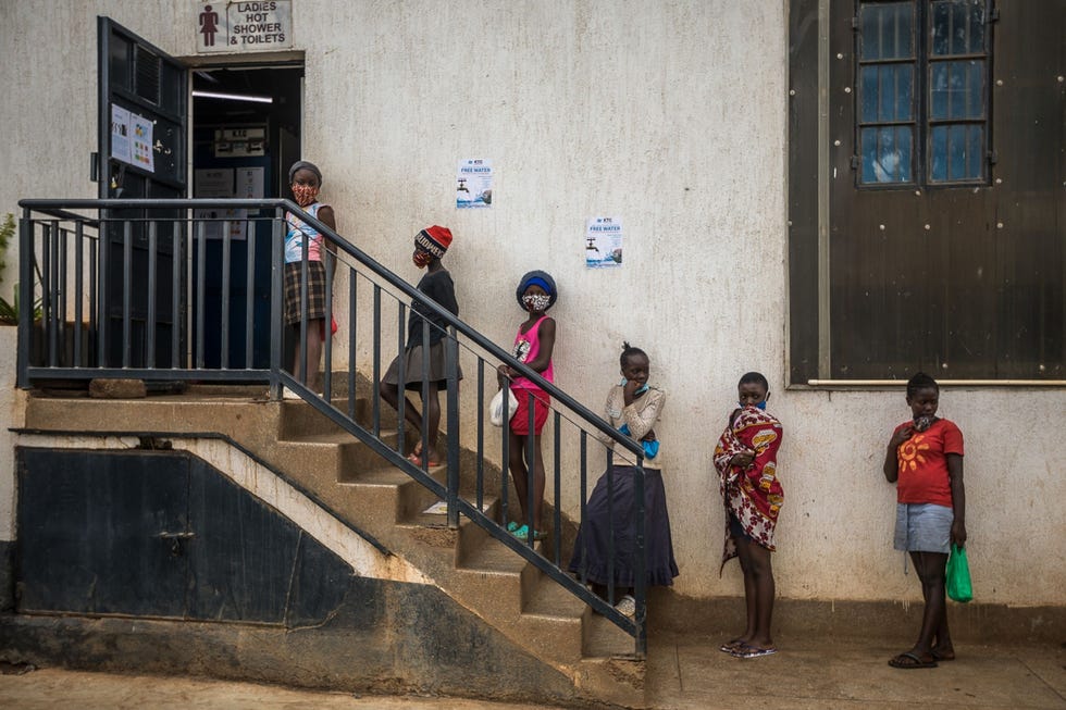 Naiorbi, Kenya NAIROBI KENIAMeisjes bewaren afstand terwijl ze in de rij staan voor een badhuis in Kibera een sloppenwijk in de Keniaanse hoofdstad Nairobi De meeste bewoners van de wijk hebben geen beschikking over eigen sanitair dus deelt een lokale organisatie gratis drinkwater uit om mensen op het gebied van persoonlijke hygine te helpen en zo de verspreiding van het coronavirus tegen te gaan