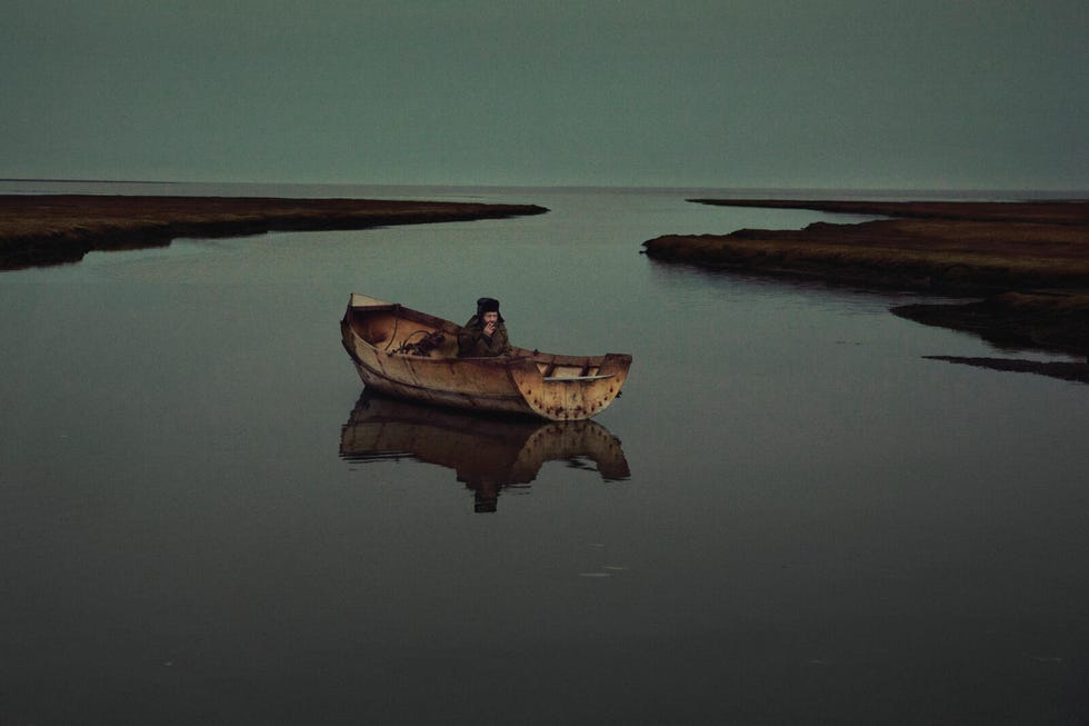 op een kalme, windstille dag ﻿dobbert vjatsjeslav korotki rond in een zelfgemaakte boot in een smalle baai van de barentszzee