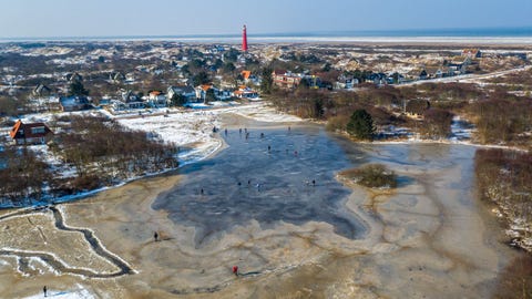 Mijn inspiratie voor deze foto waren de zogenaamde gezouten lammetjes vertelt Toala Olivares Doordat het water in de Waddenzee stijgt in de winter grazen de lammetjes in maart op zoutekwelders en krijgt hun vlees een zilte smaak Precies toen ik de hogere waterstand wilde vastleggen bevroor alles en gingen mensen massaal het ijs op zoals hier in de duinvalleien op Schiermonnikoog