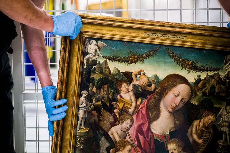 Museummedewerkers plaatsen zorgvuldig het schilderij Maria met Kind en musicerende engelen van Jacob Cornelisz van Oostsanen in de strikt geklimatiseerde schilderijenopslag