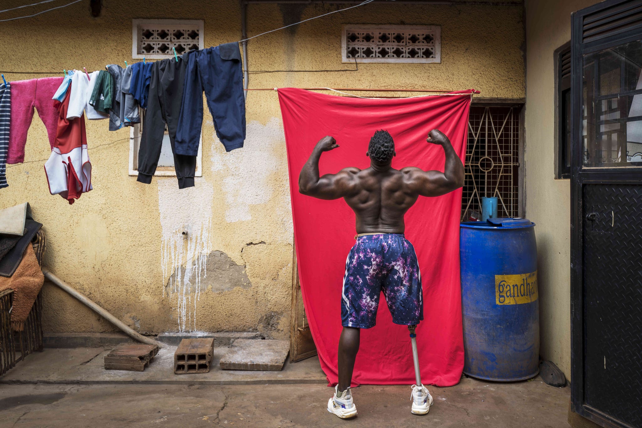 bodybuilder tamale safalu voor zijn huis in kampala