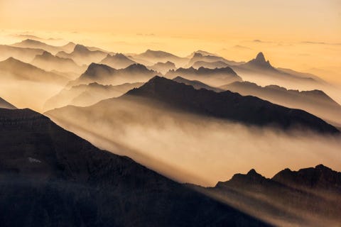 Gehuld in de rook van bosbranden die reiken tot aan de staat Washington baden de kartelige toppen van de noordelijke Rockies in Glacier National Park in het ochtendlicht Branden in het Westen worden steeds groter en destructiever naarmate de temperatuur stijgt en de droogte toeneemt