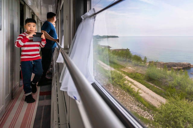 een mongolisch jongetje fotografeert het baikalmeer vanuit de rijdende trein