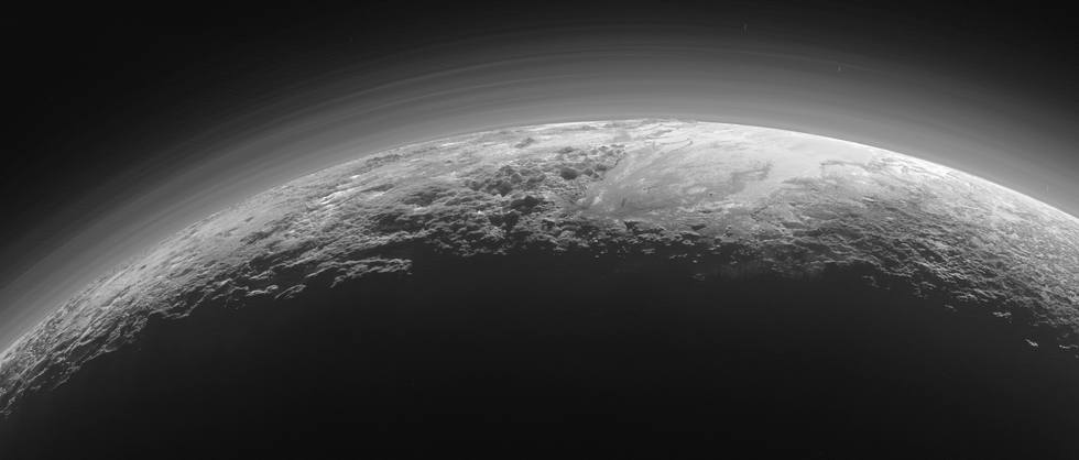 Slechts een kwartier nadat de NASAsonde New Horizons op 14 juli 2015 Pluto het dichtst was genaderd keek het ruimtevaartuig om richting de zon en maakte vlak voor zonsondergang deze opname van de grillige ijsbergen en gladde ijsvlakten die zich aan de horizon van Pluto uitstrekken Het gladde oppervlak van de uitgestrekte ijsvlakte Sputnik Planum rechts wordt in het westen links geflankeerd door woeste bergen van tot wel 3500 meter hoog waaronder de Norgay Montes op de voorgrond en de Hillary Montes aan de horizon De namen van deze bergen zijn voorlopig Rechts is een ruiger landschap ten oosten van Sputnik Planum te zien waarschijnlijk doorsneden door gletsjers In het tegenlicht zijn de talloze nevellagen van Plutou2019s ijle maar opgeblazen atmosfeer goed te zien De opname werd gemaakt op een afstand van 18000 kilometer van Pluto het in beeld gebrachte gebied is 1250 kilometer breed NASAJHUSwRI
