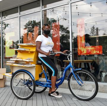 cetonia weston roy sits on her bookstore tricycle with books on display