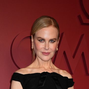 nicole kidman, a woman stands looking and the camera wearing a long black off the shoulder dress, black tights and pointed toe heels