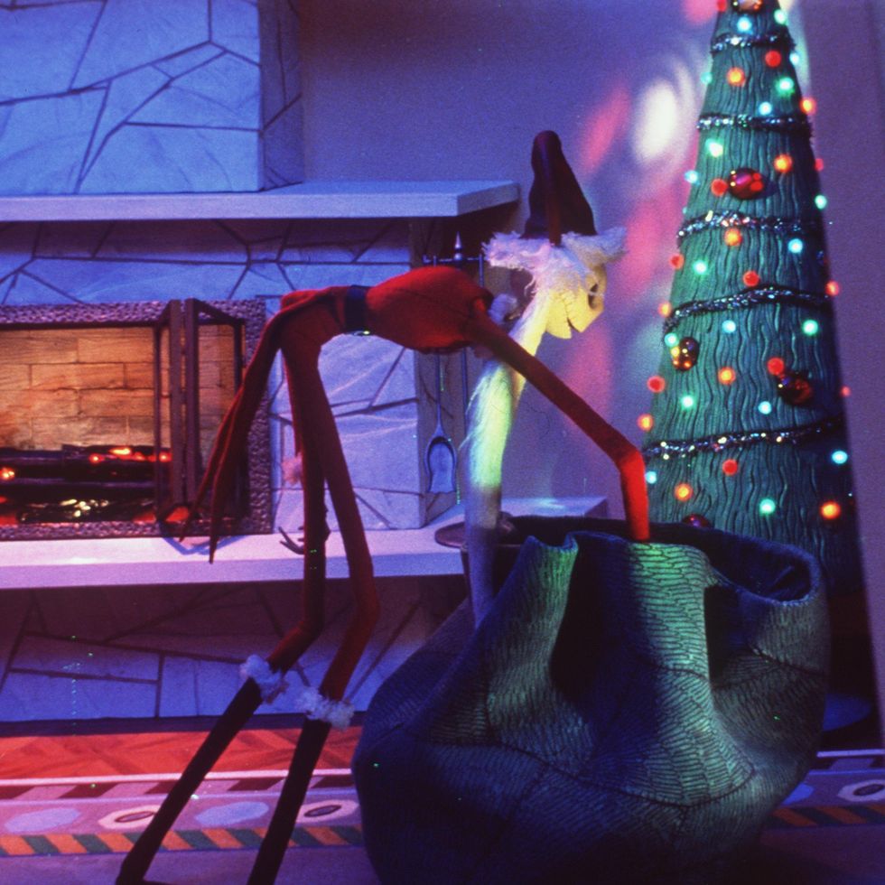 jack skellington dresses as santa and puts presents under a tree in a scene from 'the nightmare before christmas,' a good housekeeping pick for best halloween movies for kids