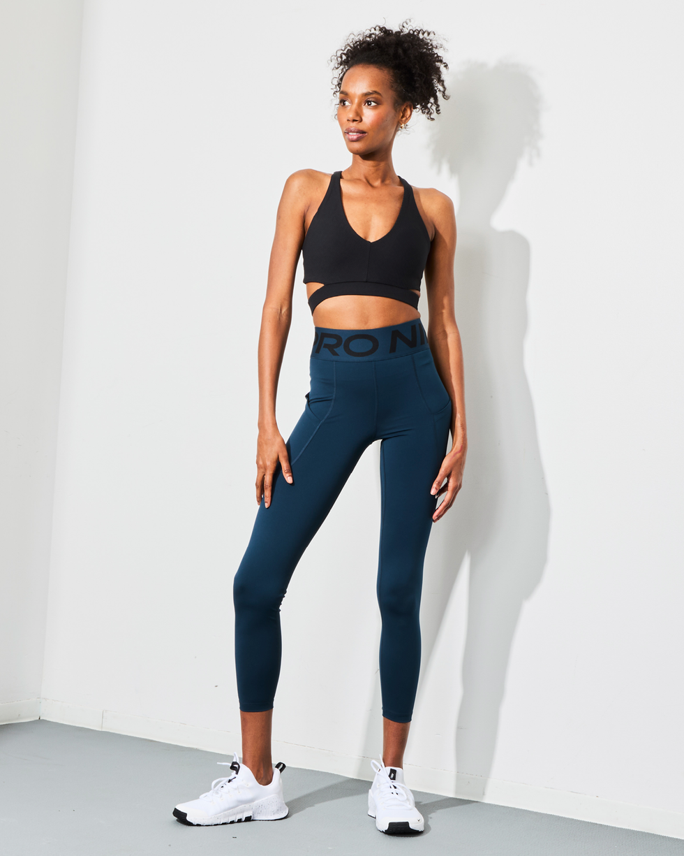 a person modeling athletic wear consisting of a black sports bra and blue leggings