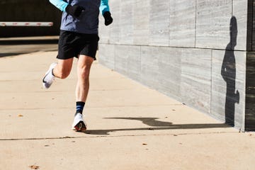 a man running on a sidewalk with focus on the shin