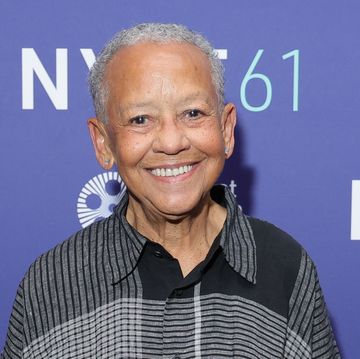 nikki giovanni smiles at the camera, she wears a black and grey patterned collared shirt