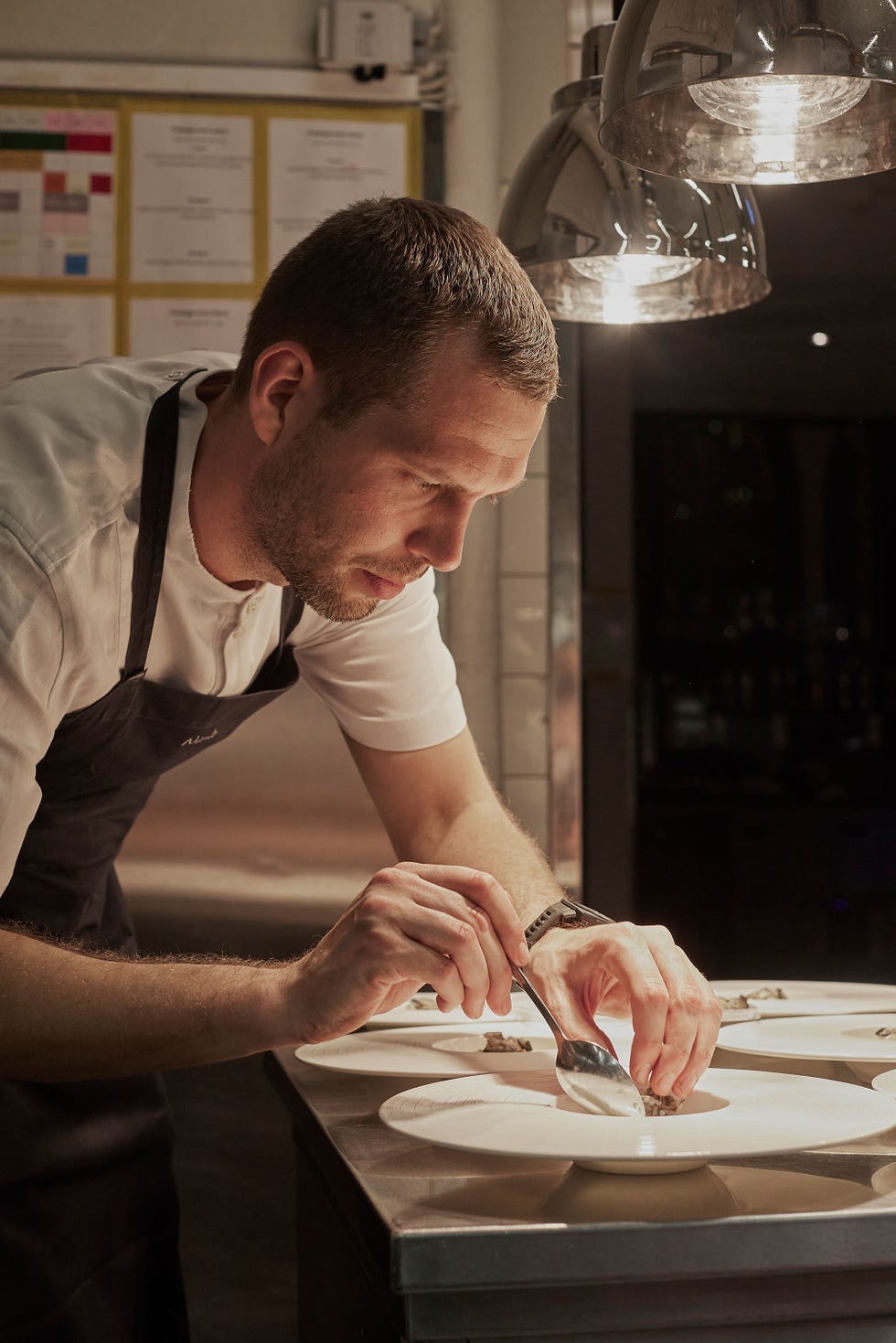 a chef meticulously plating food in a professional kitchen