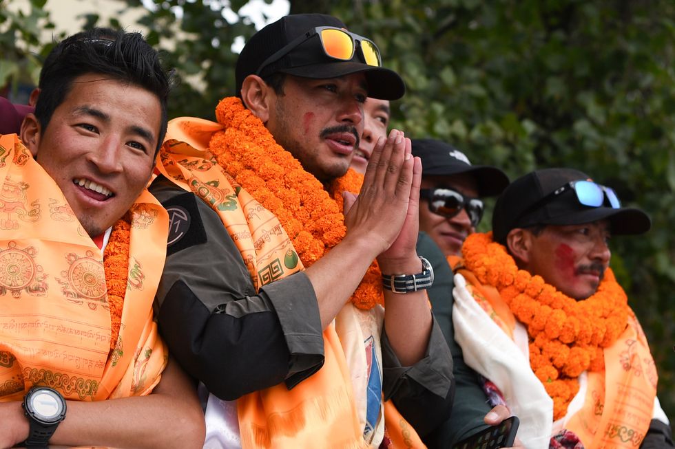 topshot   nepali mountaineer nirmal purja c gestures next to teammate mingma david sherpa r after arriving in tribhuvan airport in nepals capital kathmandu on october 30, 2019   a nepali mountaineer on october 29 smashed the speed record for summiting the worlds 14 highest peaks, racing up all 8000ers in just six months and six days, organisers said the previous record for the 14 mountains above 8,000 metres around 26,250 feet    completed by nirmal purja at 859 am 1259 gmt on october 29    was almost eight years photo by prakash mathema  afp photo by prakash mathemaafp via getty images