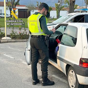 a person in a yellow vest standing next to a white car