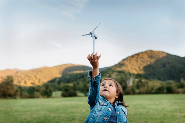 una nina sostiene una maqueta de un molino de energia sostenible