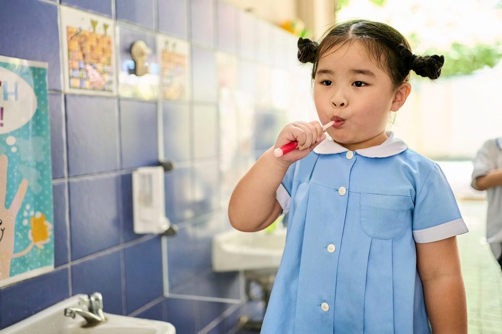 una nina se lava los dientes con un cepillo