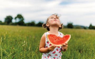niña pequeña disfrutando de una sandía en el campo