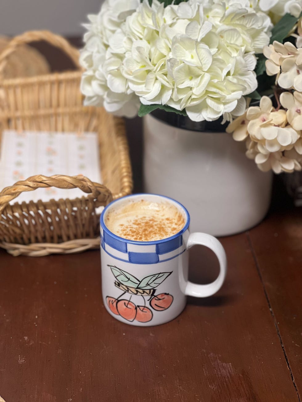 a kitchen table with flowers and a mug of coffee on it