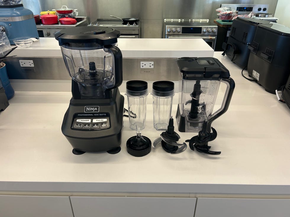 blender with various containers and blades on a kitchen counter