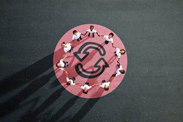 unos ninos con uniforme escolar cogidos de la mano sobre un circulo rojo en un patio
