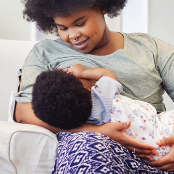 woman breastfeeding baby in living room