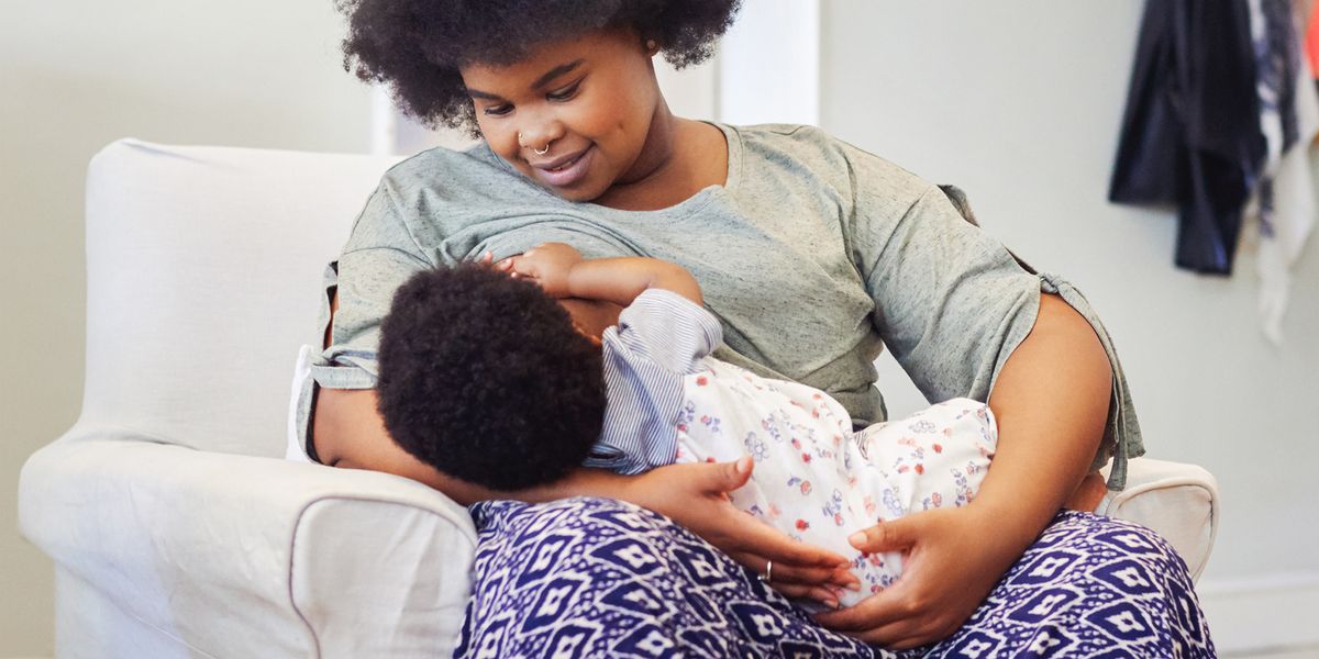 woman breastfeeding baby in living room