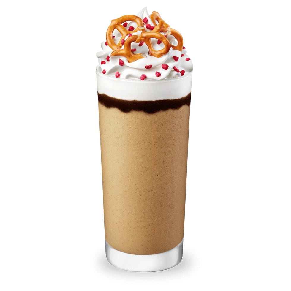frosted beverage in a tall glass with whipped cream and pretzel topping