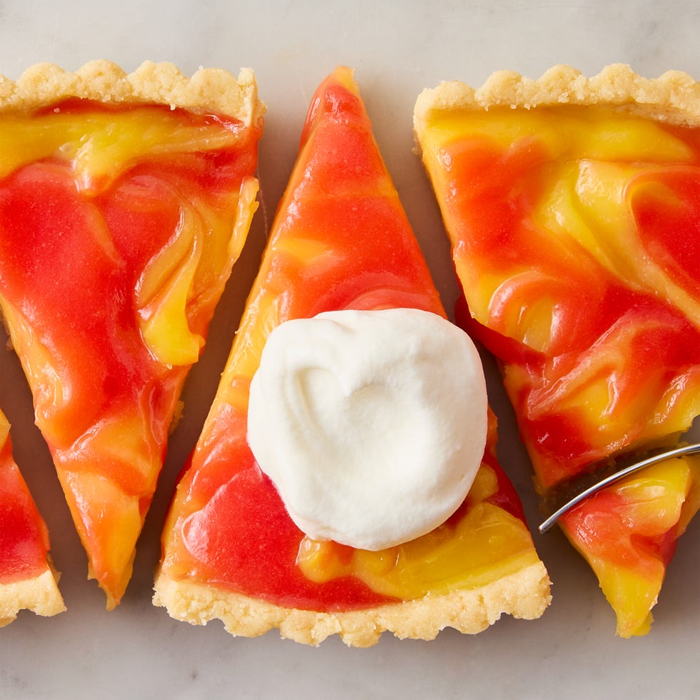 a tart made with cookie crust and a filling of lemon and strawberry curds swirled together. served with whipped cream on the side