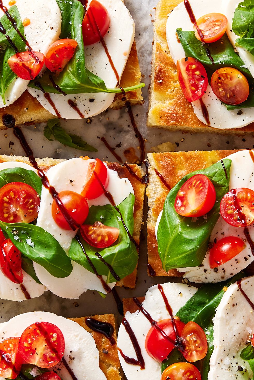no knead focaccia topped with mozzarella, basil, cherry tomatoes and drizzled with balsamic