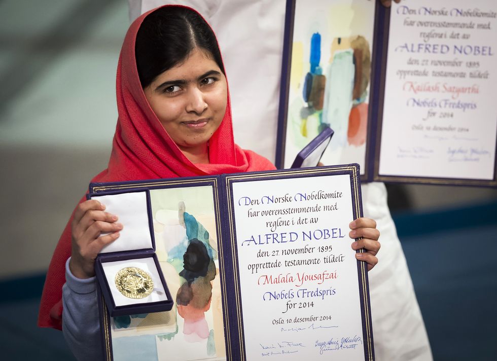 malala yousafzai holding a medal and diploma open for photos