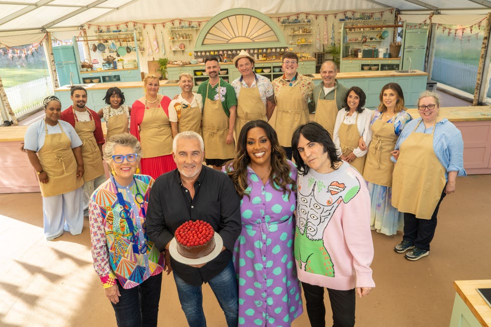 baking competition participants posing in a kitchen setting with a cake