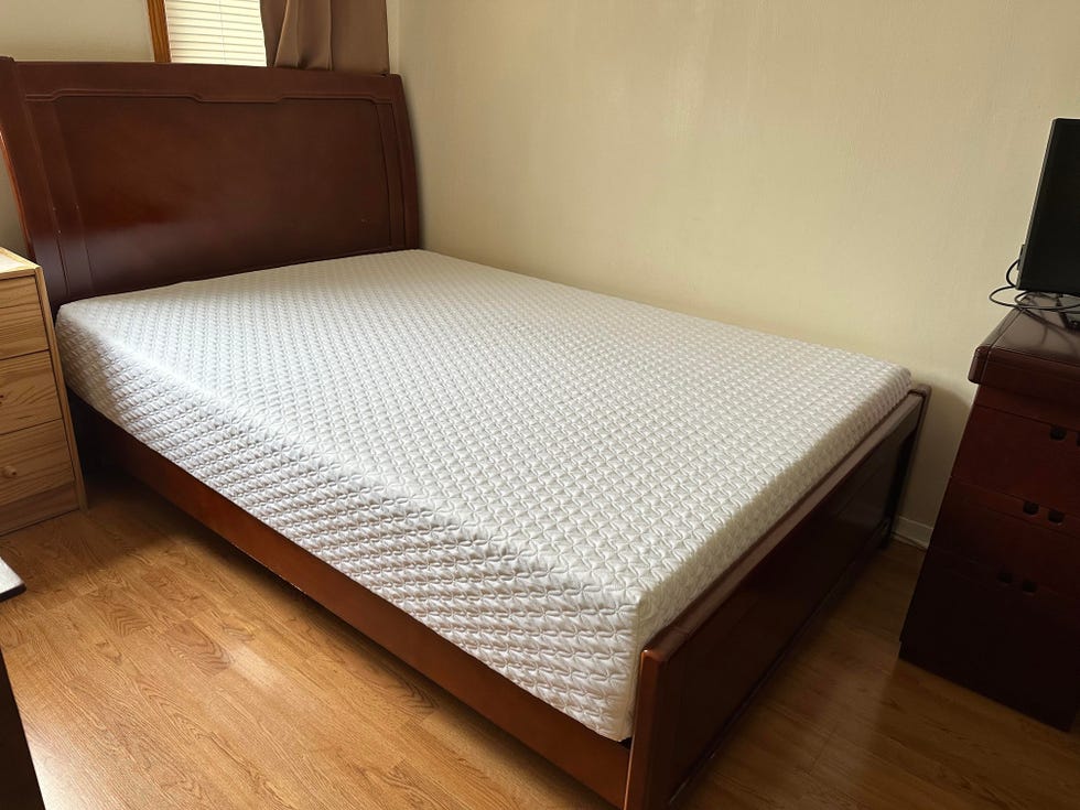 a white memory foam mattress from nolah on a brown wooden bed frame with a tall headboard