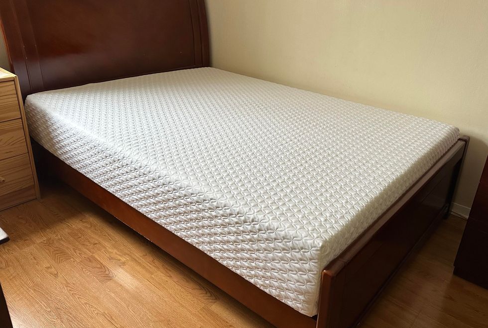 a picture of a white memory foam mattress from nolah on a brown wooden bed frame with a tall headboard