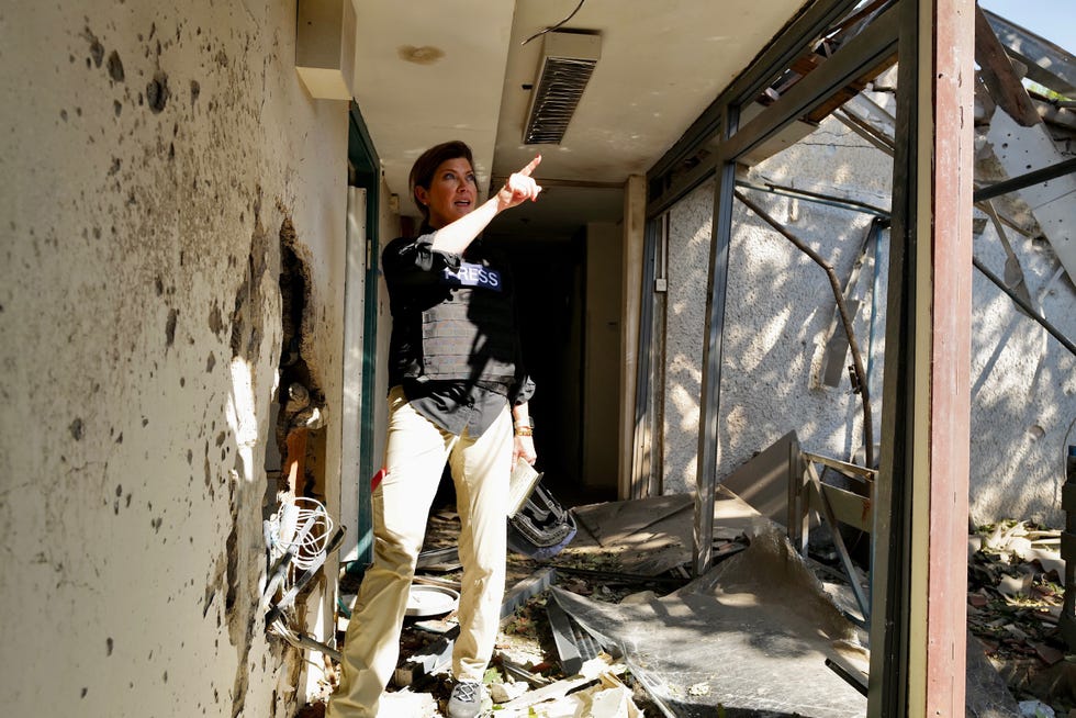 a journalist in a damaged interior space pointing and examining the surroundings