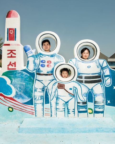 In een waterpark in Pyongyang poseert een gezin achter een eerbetoon aan het ruimtevaartprogramma