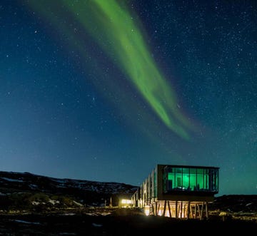 a house with a green aurora in the sky above it