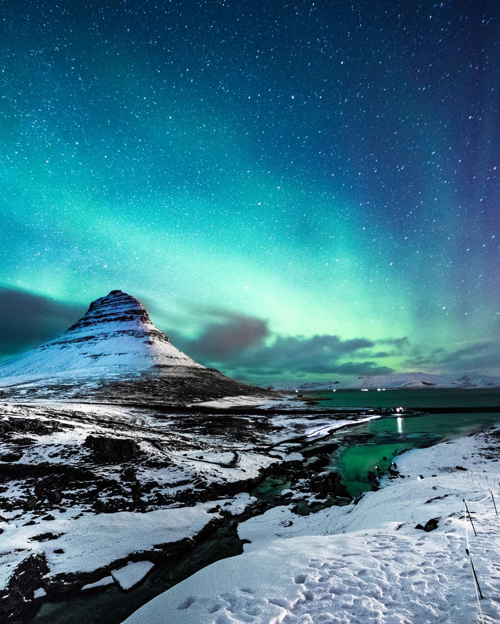 northern lights in mount kirkjufell iceland with a man passing by