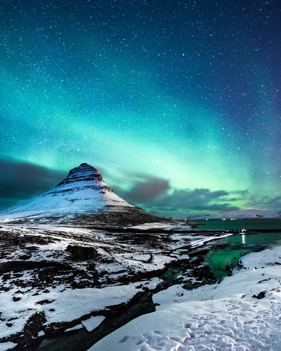 northern lights in mount kirkjufell iceland with a man passing by