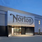 a metal clad industrial building with "norton motorcycles" written above the doorway entrance