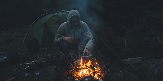Norway, Lofoten, Moskenesoy, Young man sitting at camp fire