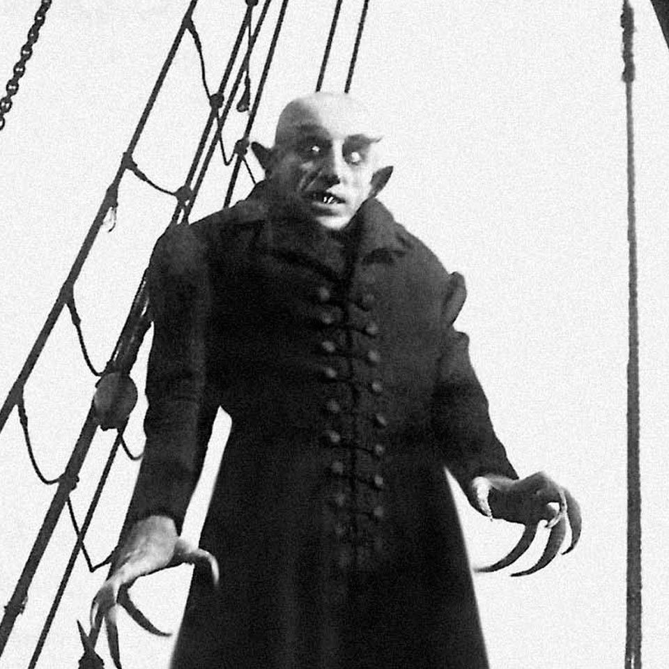 a scene from the classic horror movie nosferatu featuring the titular creature leering in black and white