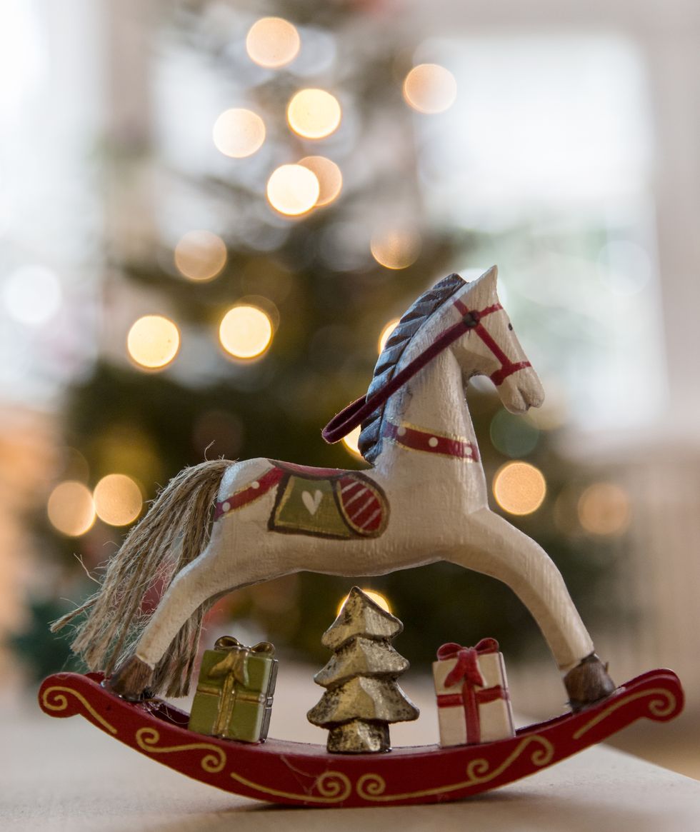 Nostalgic deocrative rocking horse before a lit Christmas tree