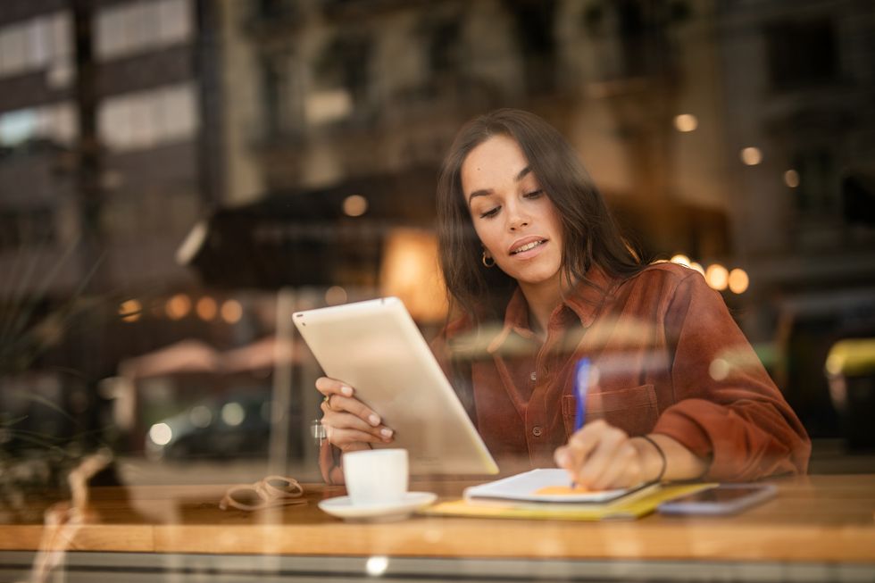 portrait of an attractive young woman enjoying a beautiful day sitting in her favorite seat by the window in a coffee shop working online on her digital devices