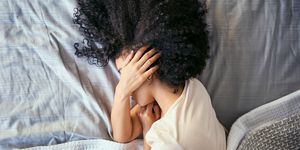 woman laying in bed with a headache