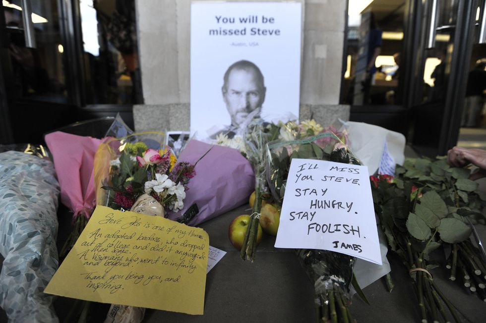 flowers notes and apples rest in front of a photograph of steve jobs