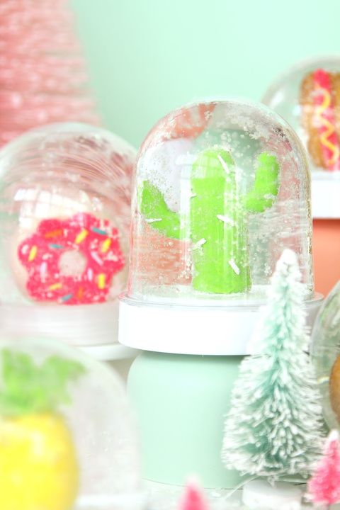 a snowglobe with a donut and a snowglobe with a cactus against a fun festive background of winter crafts