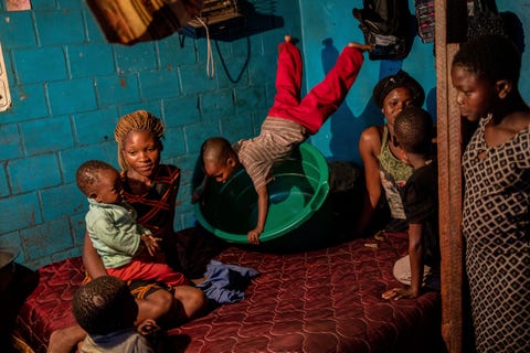 Een kind speelt met een lege waskom nadat zijn moeder en grootmoeder de was hebben gedaan In dit kleine appartement in Mbare het eerste dichtbevolkte township in Zimbabwe verzamelen drie generaties vrouwen en kinderen zich in de kamer waar ze studeren lachen en slapen